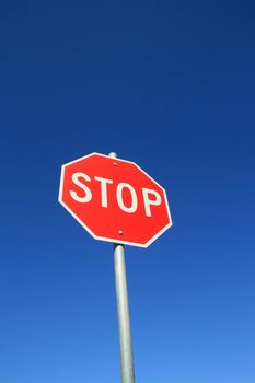 Stop road sign over clear blue sky.
