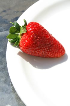 Close up of a strawberry on a plate.
