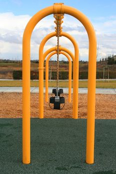 A row of swings in a playground.
