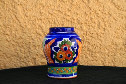 Talavera handpainted ceramic jar over cream and black background.
