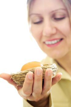 Mature woman holding a nest with an egg - investment concept