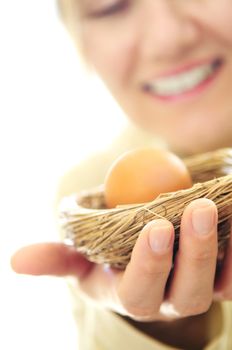 Mature woman holding a nest with an egg - investment concept