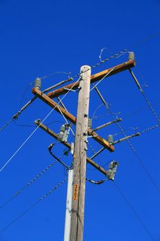 Close up of a telephone pole over blue sky.
