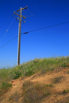 Close up of a telephone pole on a hilltop.
