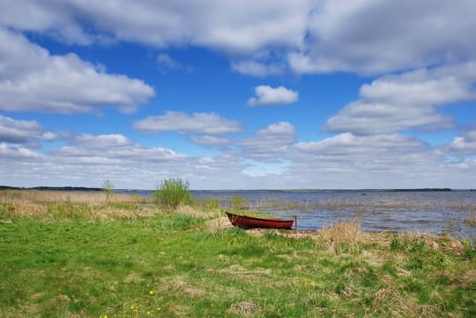 Spring landscape by the lake with a red boat