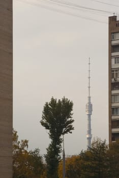 Ostankino communication tower, viewed between two residential buildings against hazy autumn sky