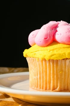 Close up of a muffin with cream frosting on a plate.
