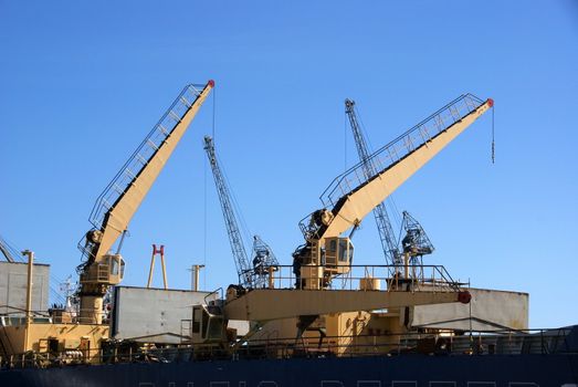 Three ship cranes on a deck of the cargoship