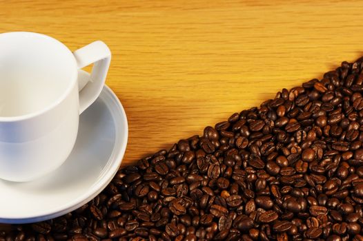 Dark roasted coffee beans with a white cup and saucer