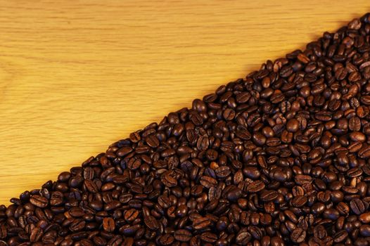 Dark roasted coffee beans on an oak table top with room for advert