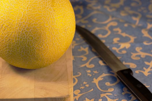 A galia melon on a chopping board with a sharp knife