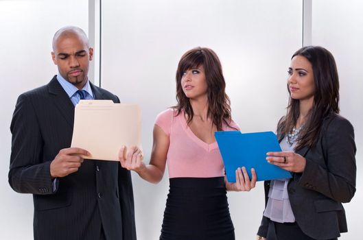 Young woman giving tasks to her colleagues who look skeptical.