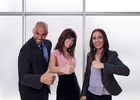 Young multiethnic business team smiling and showing thumbs up.