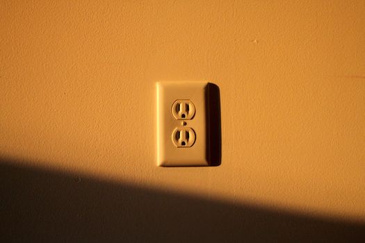 Abstract view of a wall socket with the late sun splashing