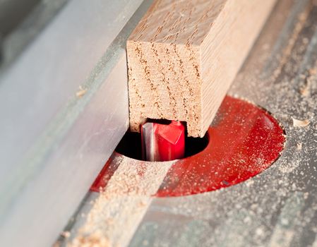 Close up of a straight router bit cutting a groove or rabbet in a piece of oak