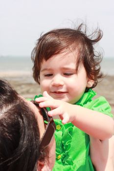 Baby playing with mother taking her sunglasses