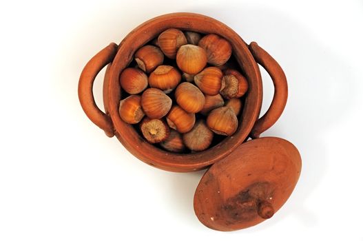 pot with hazelnuts, pine nuts surrounded, isolated, close-up, top view
