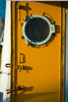 Yellow steel door with round window inside boat