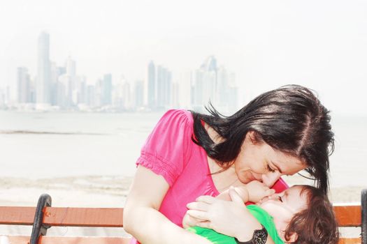 Mother playing with her baby with the city in the background