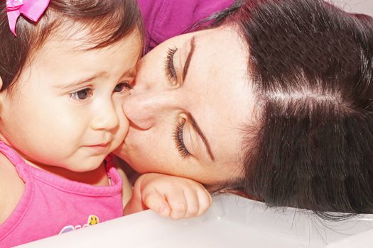 photo of a Mother kissing her daughter .