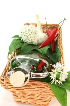 Wild garlic oil with chili, colored pepper, garlic and leaves and flowers in a basket