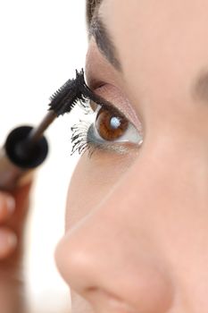 closeup of young brown eyed lady applying mascara using lash brush