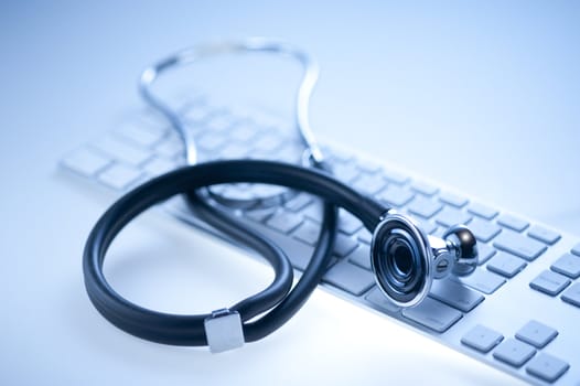 Medical stethoscope on a computer keyboard in blue, closeup