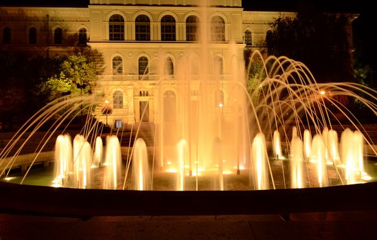 Beautifully lit fountain at night on a square in downtown Szeged, Hungary.