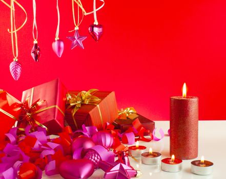 Christmas gifts and candles over red background