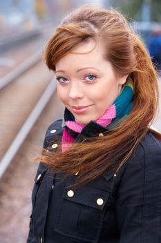 Teenage girl at railway platform, looking at camera, smiling