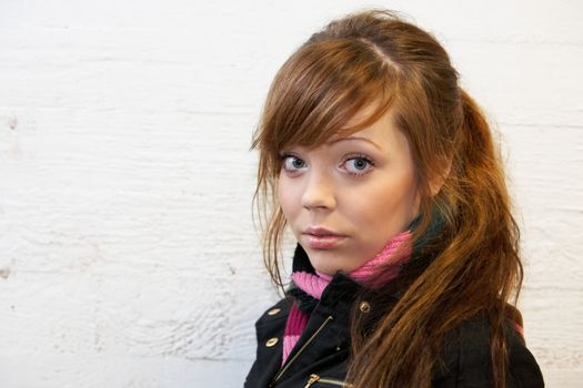 Teenage girl by wall, looking at camera, interior