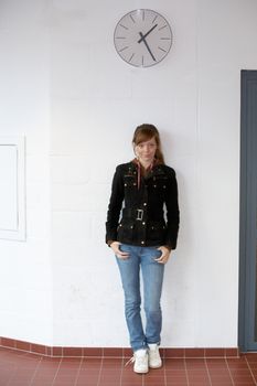 Teenage girl standing under large wall clock