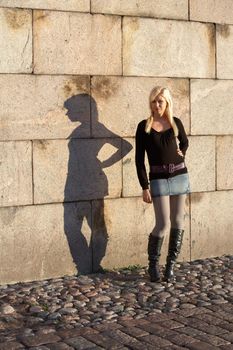 Teenage girl standing on sidewalk, shadow on wall
