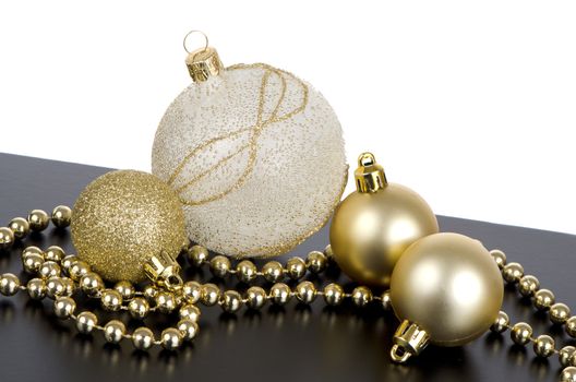 Golden christmas ball on black surface with white background.