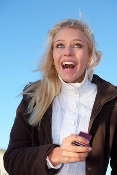 Teenage girl holding mobile phone, laughing