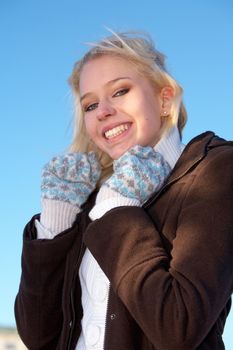 Teenage girl wearing warm gloves, looking at camera, smiling