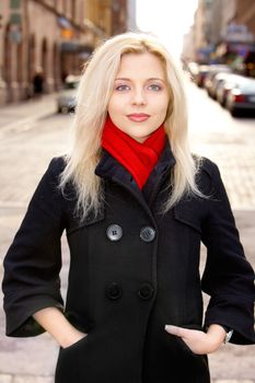 Young woman in street, looking at camera, hands in pockets