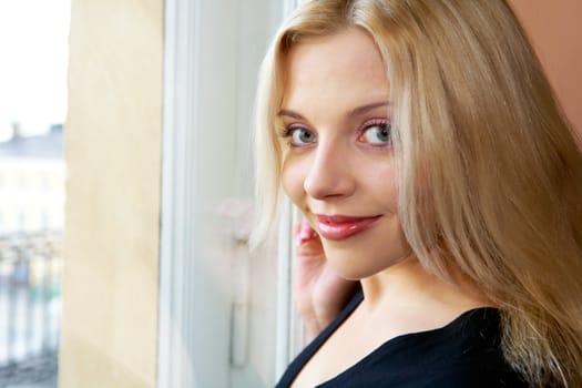 Young woman beside window, looking at camera