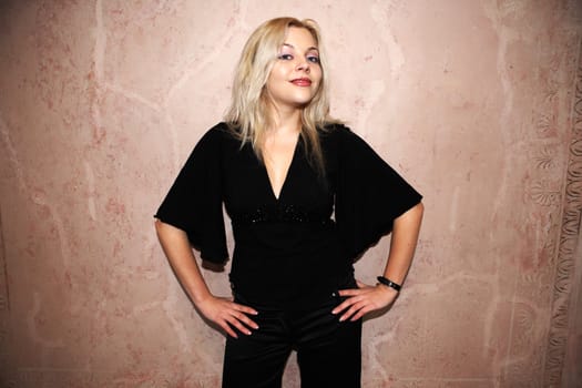 Young woman standing before wall, looking at camera