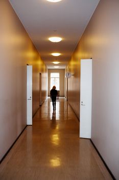 Woman in corridor, walking away, open doors