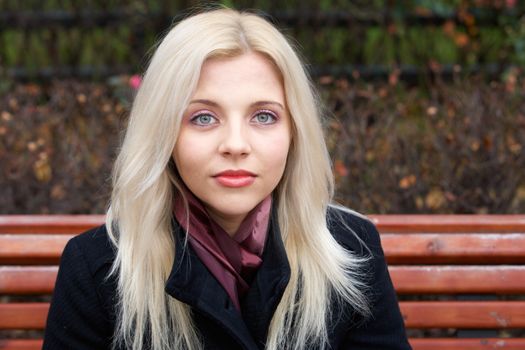 Young woman on bench, looking at camera