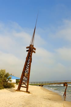 Old rusty metal tilted tower with lightning rod on the seashore. Kinburn Spit near Ochakiv, Ukraine