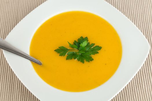 Dish with carrot soup and  garnish parsley.