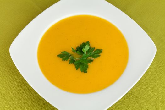 Dish with carrot soup and  garnish parsley.