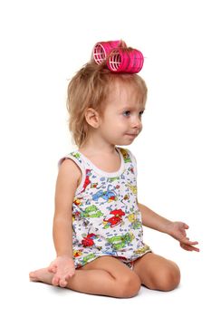 Little girl with pink hair curlers on her head on the white background
