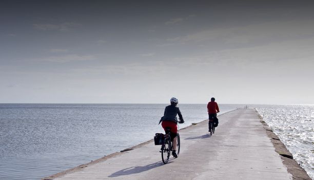 Cyclists ride on concrete pier in the Curonian Lagoon.