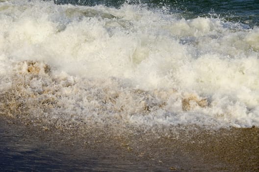 Waves carrying sea sand on shore. Natural water shattering backdrop.