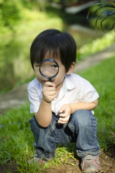 Little boy exploring nature by magnifier