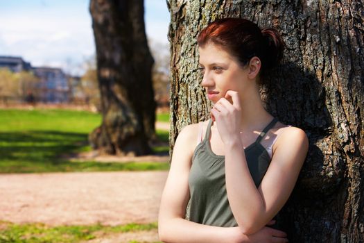 Teenage girl leaning to tree in park
