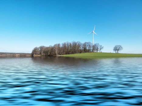 Wind turbine in the countryside reflecting on a lake